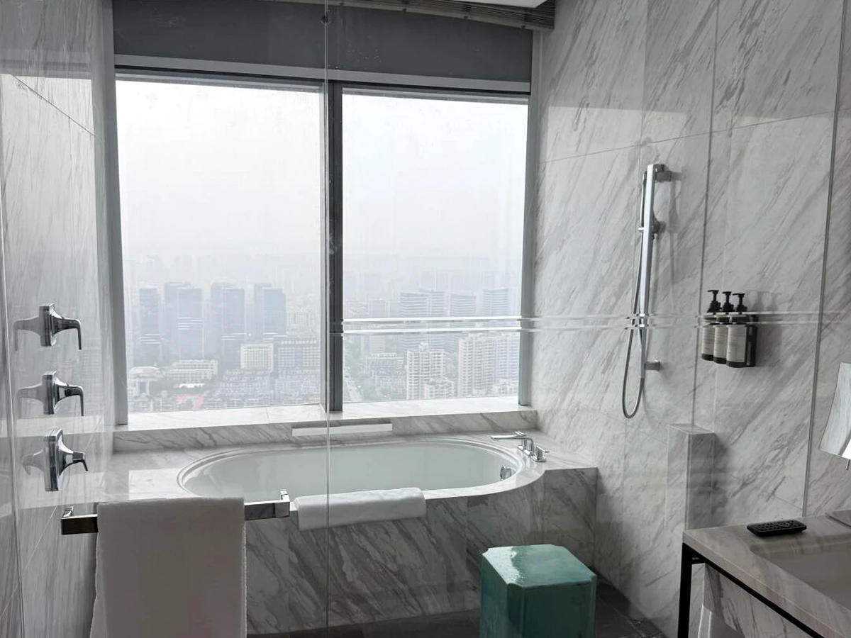 Bathroom hardware installation with wall-mounted accessories beside a marble bathtub and shower