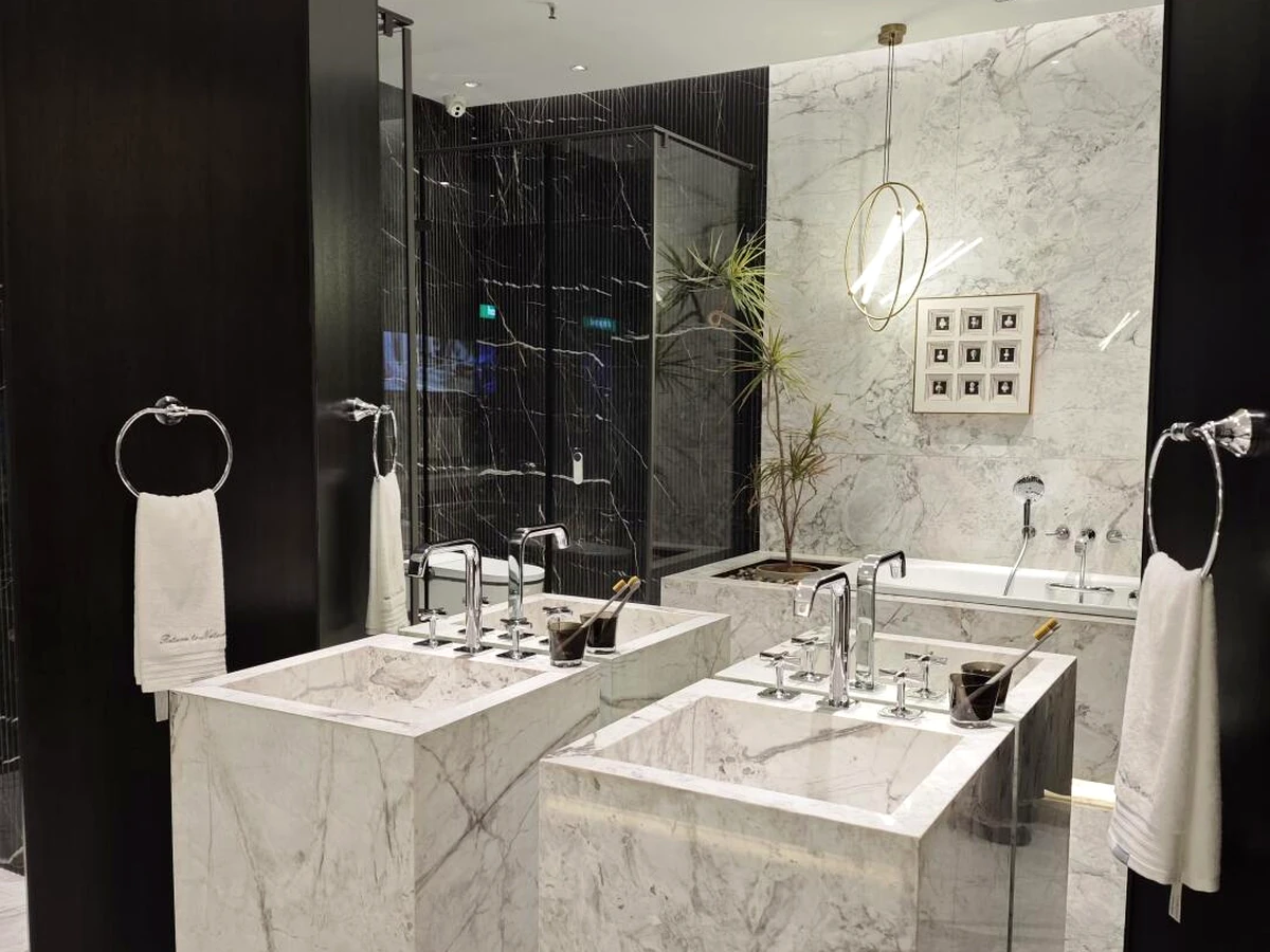 Wall-mounted chrome-finish towel rings installed beside twin marble washbasins in a bathroom.